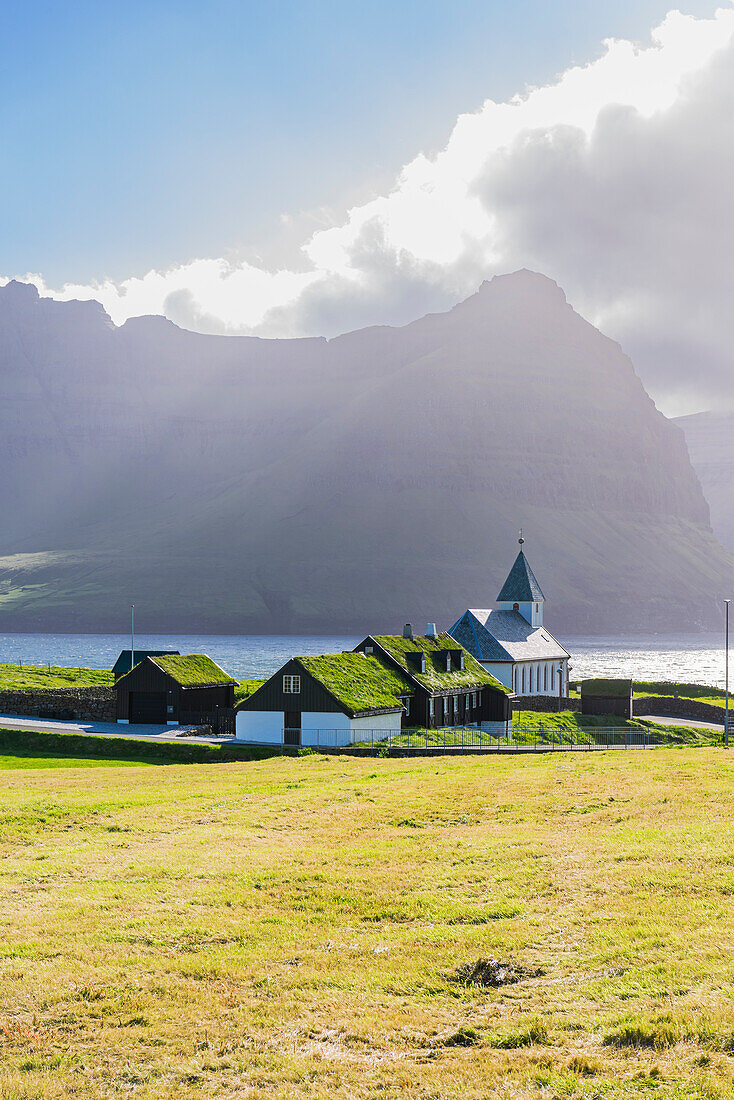 View of the church and grass roof houses in the village of Vidareidi at sunset, Vidoy island, Faroe Island, Denmark, Europe