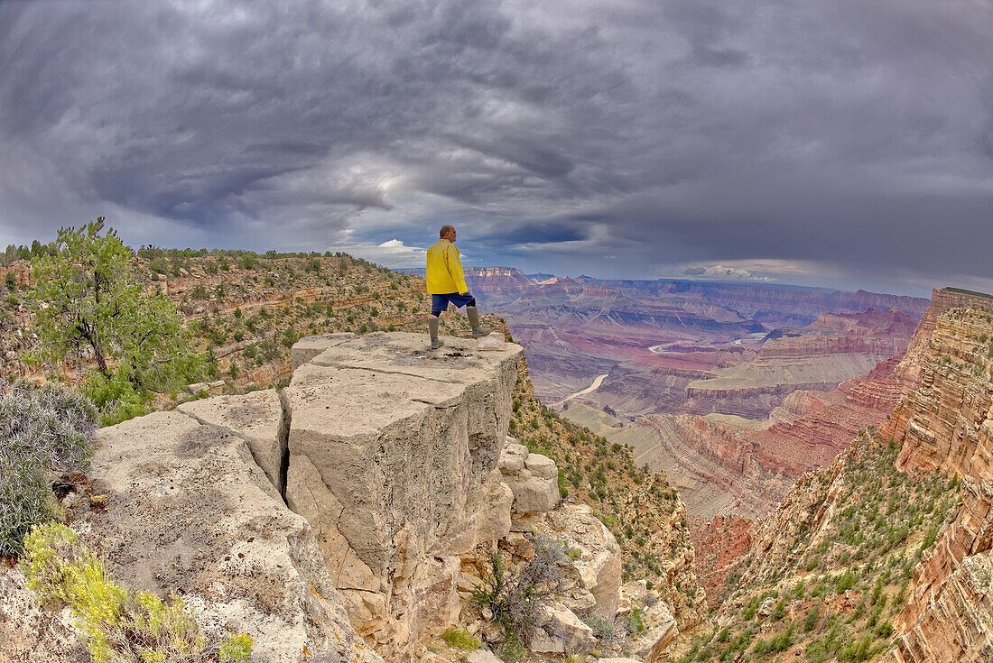 A hiker standing on a cliff between Zuni and Papago Points at Grand Canyon on a stormy day, Grand Canyon National Park, UNESCO World Heritage Site, Arizona, United States of America, North America
