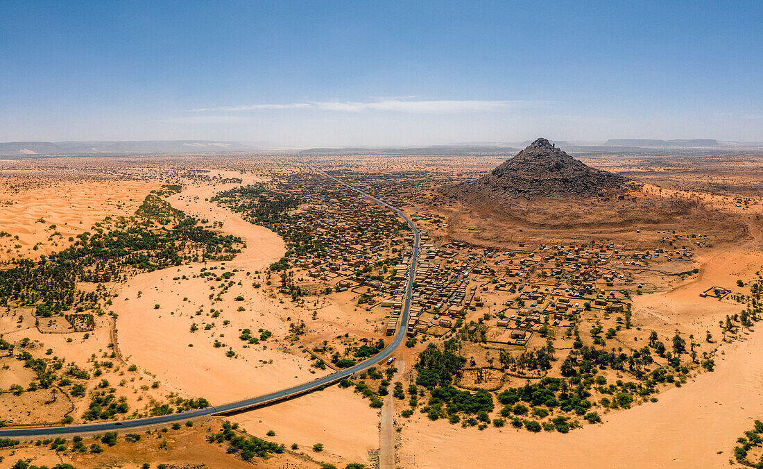Ein bröckelnder Berg, ein Flussbett, Palmen und Dünen umgeben das Dorf Kamour, Mauretanien, Sahara-Wüste, Westafrika, Afrika