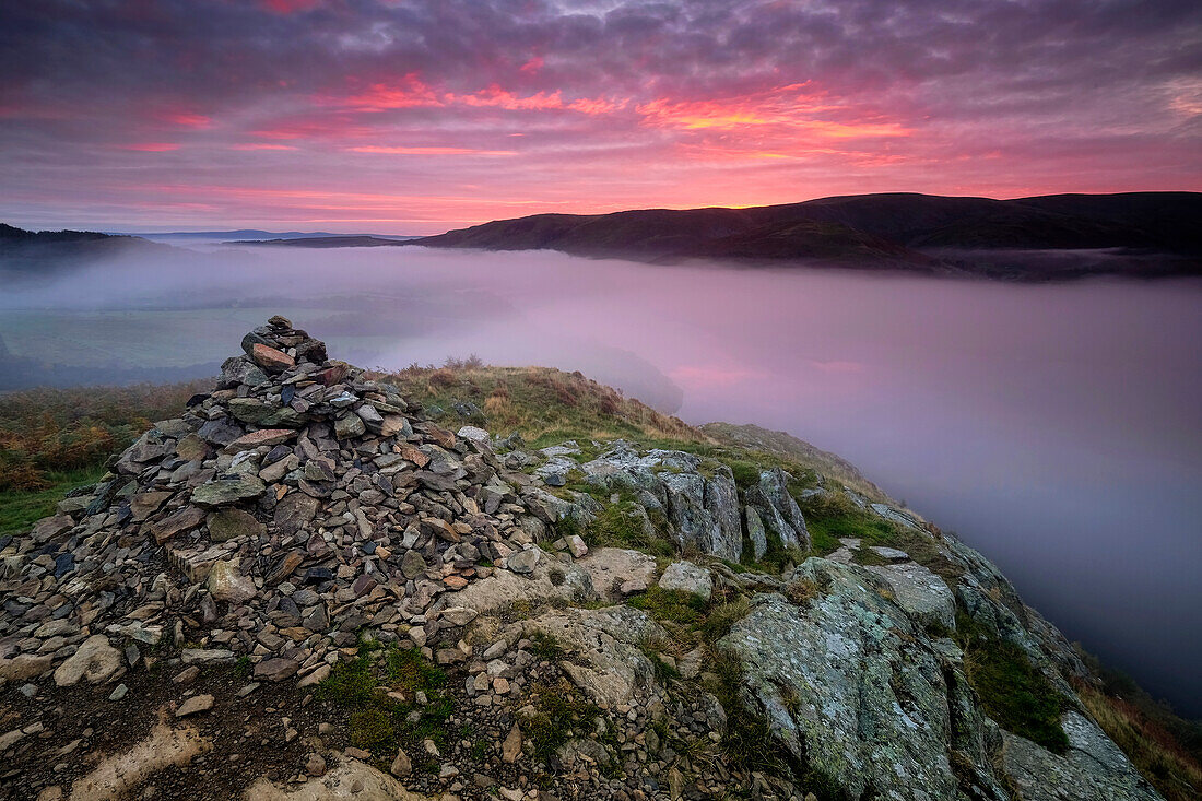 Summit Cairn auf Yew Crag über dem nebligen Ullswater bei Sonnenaufgang, Gowbarrow Fell, Lake District National Park, UNESCO-Weltnaturerbe, Cumbria, England, Vereinigtes Königreich, Europa