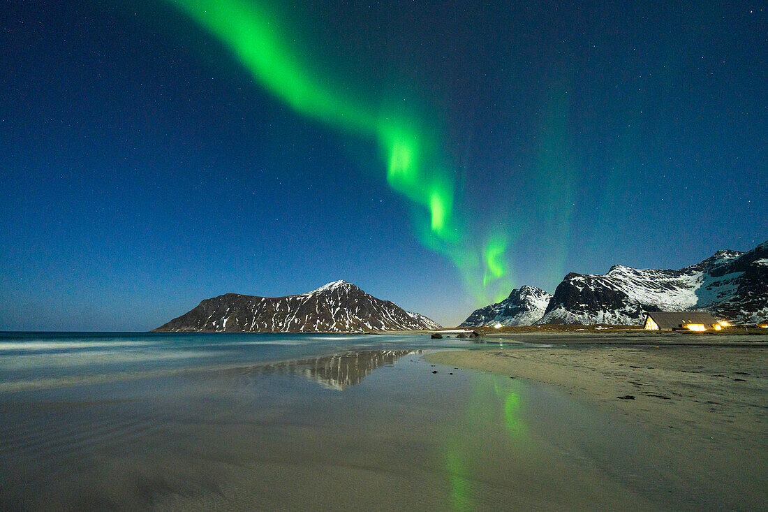 Nordlicht (Aurora Borealis) über schneebedeckten Bergen mit Blick auf den Strand von Skagsanden, Ramberg, Landkreis Nordland, Lofoten, Norwegen, Skandinavien, Europa