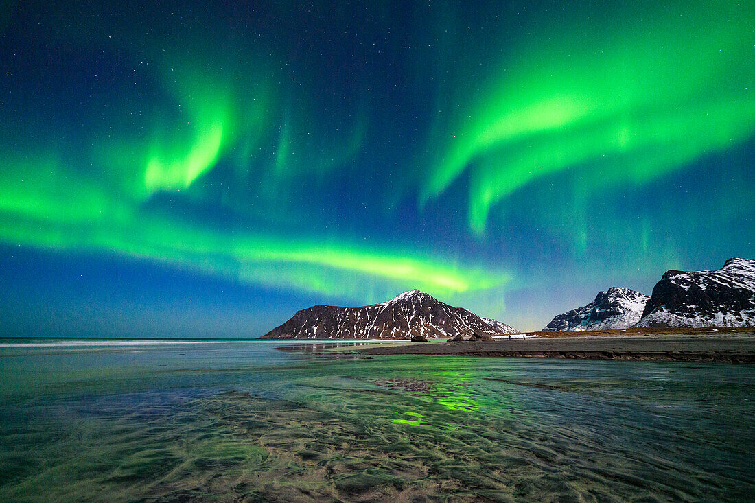 Skagsanden Strand unter dem hellen Nordlicht (Aurora Borealis), das sich im Meer spiegelt, Ramberg, Landkreis Nordland, Lofoten Inseln, Norwegen, Skandinavien, Europa