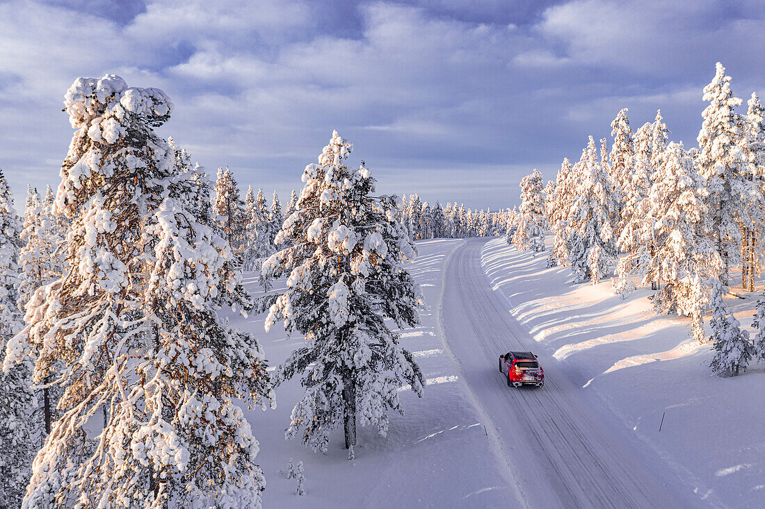 Blick von oben auf einen Geländewagen, der auf einer vereisten Piste zwischen schneebedeckten Bäumen fährt, Kangos, Lappland, Schweden, Skandinavien, Europa