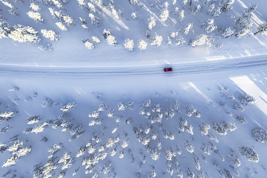 Draufsicht auf ein Auto, das auf einer kurvenreichen Straße im verschneiten Winterwald fährt, Kangos, Norrbotten County, Lappland, Schweden, Skandinavien, Europa