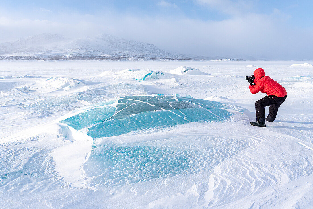 Mann fotografiert die schneebedeckte arktische Landschaft auf einem zugefrorenen See, Norrbotten County, Lappland, Schweden, Skandinavien, Europa