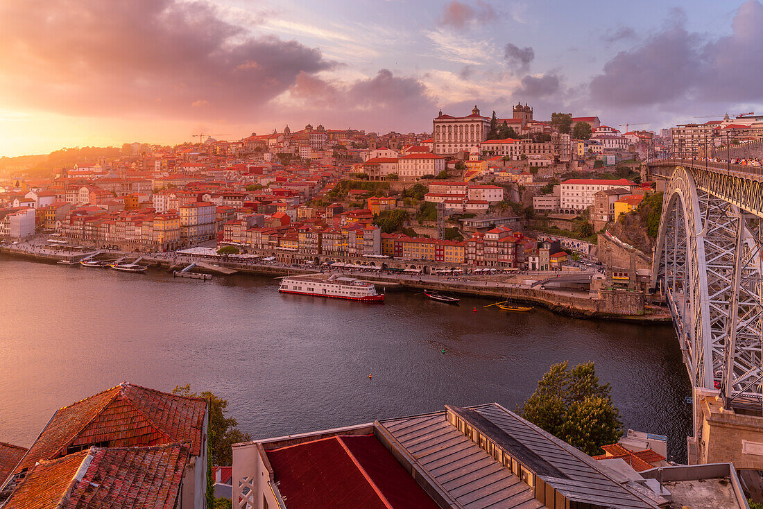 View of the Dom Luis I bridge over Douro River aligned with colourful buildings at sunset, looking towards the Ribeira district, UNESCO World Heritage Site, Porto, Norte, Portugal, Europe
