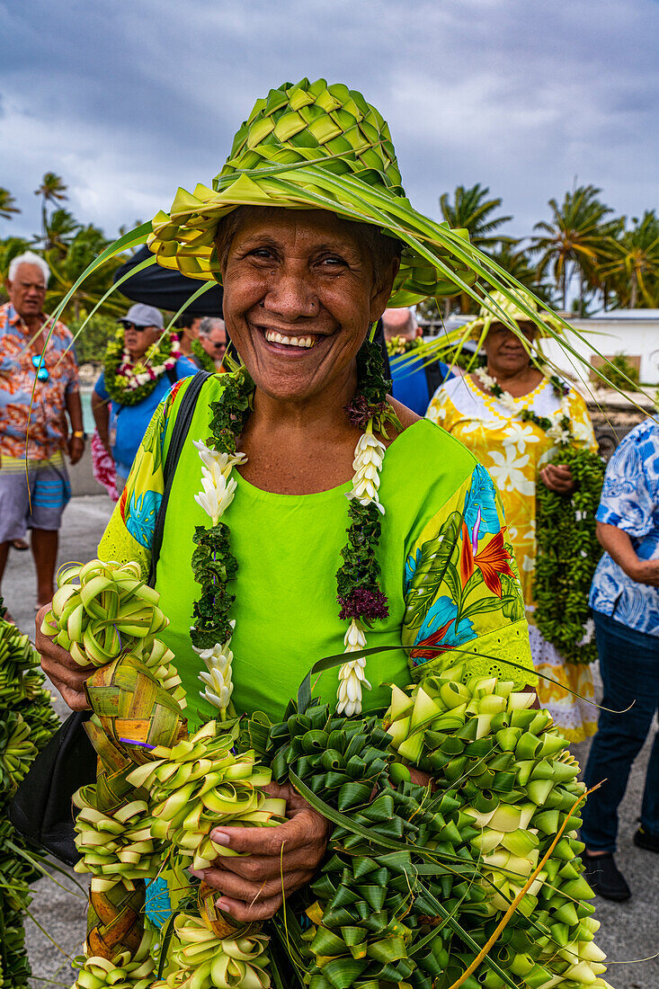 Bunt gekleidete Frau mit gewebtem Hut auf dem Kopf, Hikueru, Tuamotu-Archipel, Französisch-Polynesien, Südpazifik, Pazifik