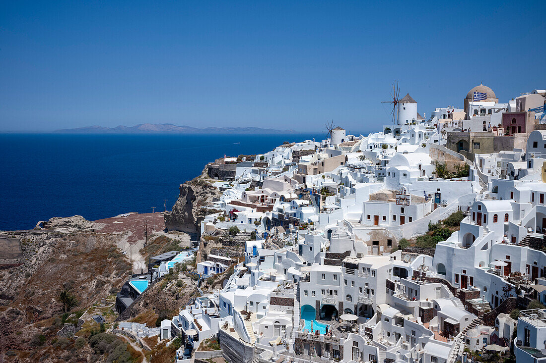 Windmills, houses and hotels in the town of Oia, on the clifftop overlooking the caldera, Santorini, The Cyclades, Aegean Sea, Greek Islands, Greece, Europe