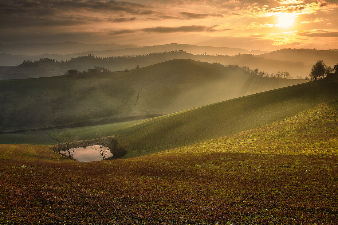 Sonnenuntergang über italienischer Landschaft und Hügeln mit einem kleinen See, Italien, Europa