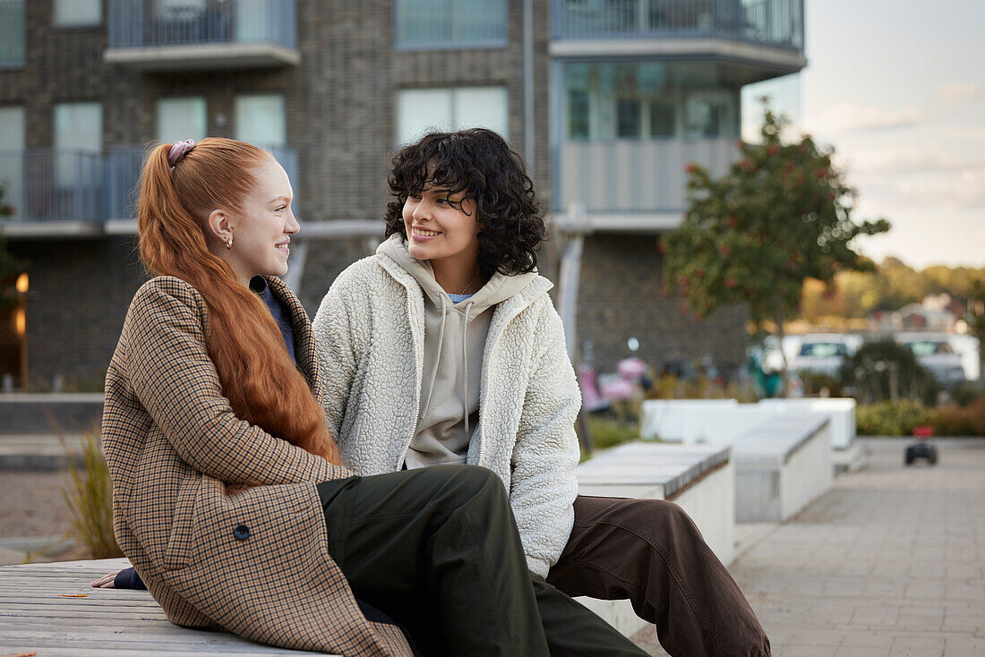 Young female friends sitting outdoors