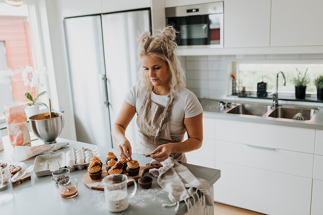 Woman in kitchen preparing cupcakes