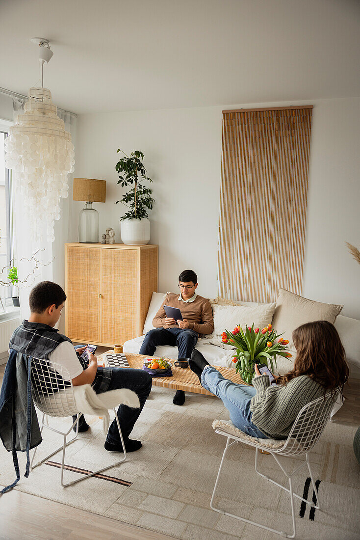 Geschwister, die zu Hause Telefone und Tablets benutzen