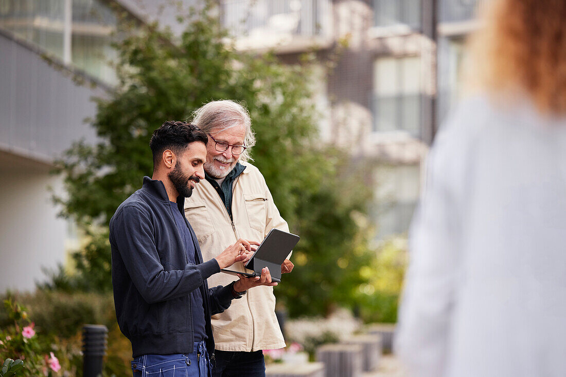 Two men with laptop in courtyard