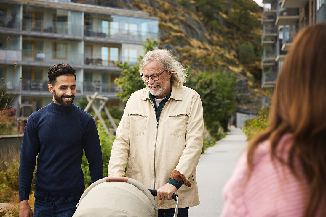 Men with baby stroller walking in residential area