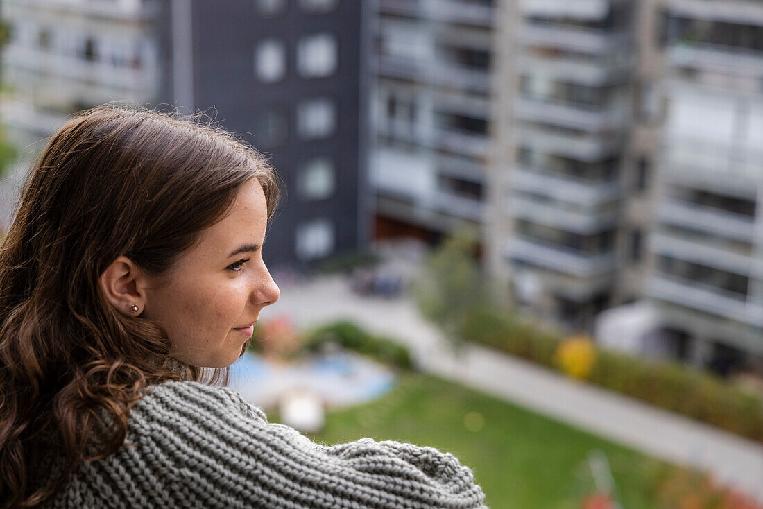 Lächelndes Teenager-Mädchen blickt vom Balkon auf die Aussicht