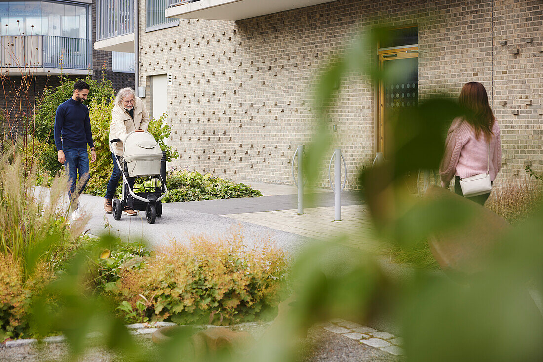 Men pushing pram in front of block of flats