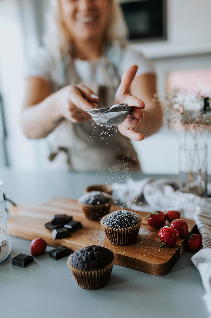 Frau in Küche bei der Zubereitung von Cupcakes