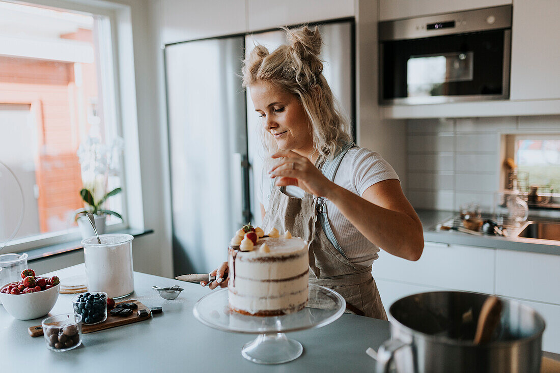 Frau in der Küche beim Verzieren von Kuchen