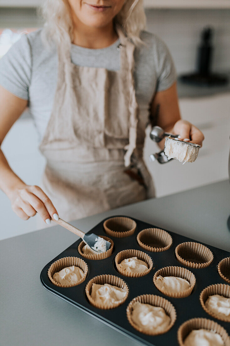 Frau in Küche bei der Zubereitung von Cupcakes