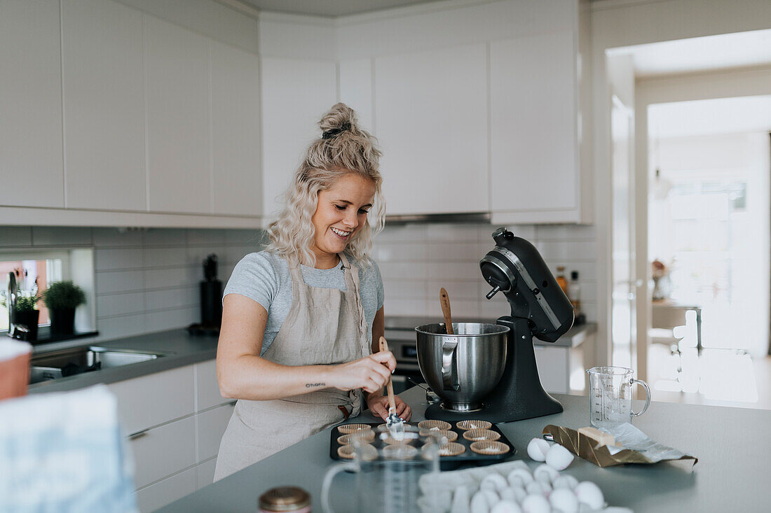 Woman in kitchen preparing cupcakes