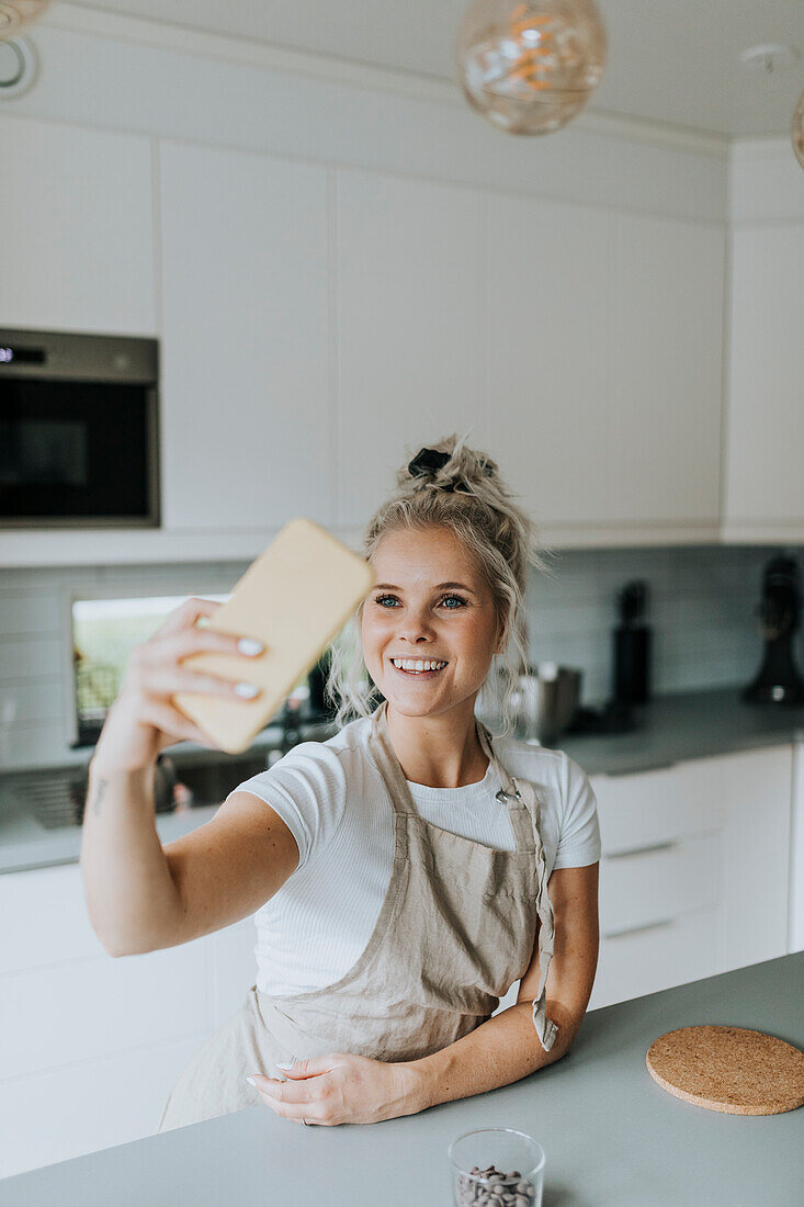 Lächelnde Frau macht Selfie in der Küche