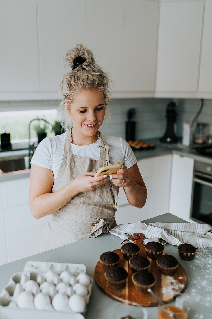 Woman taking picture of freshly baked cupcakes