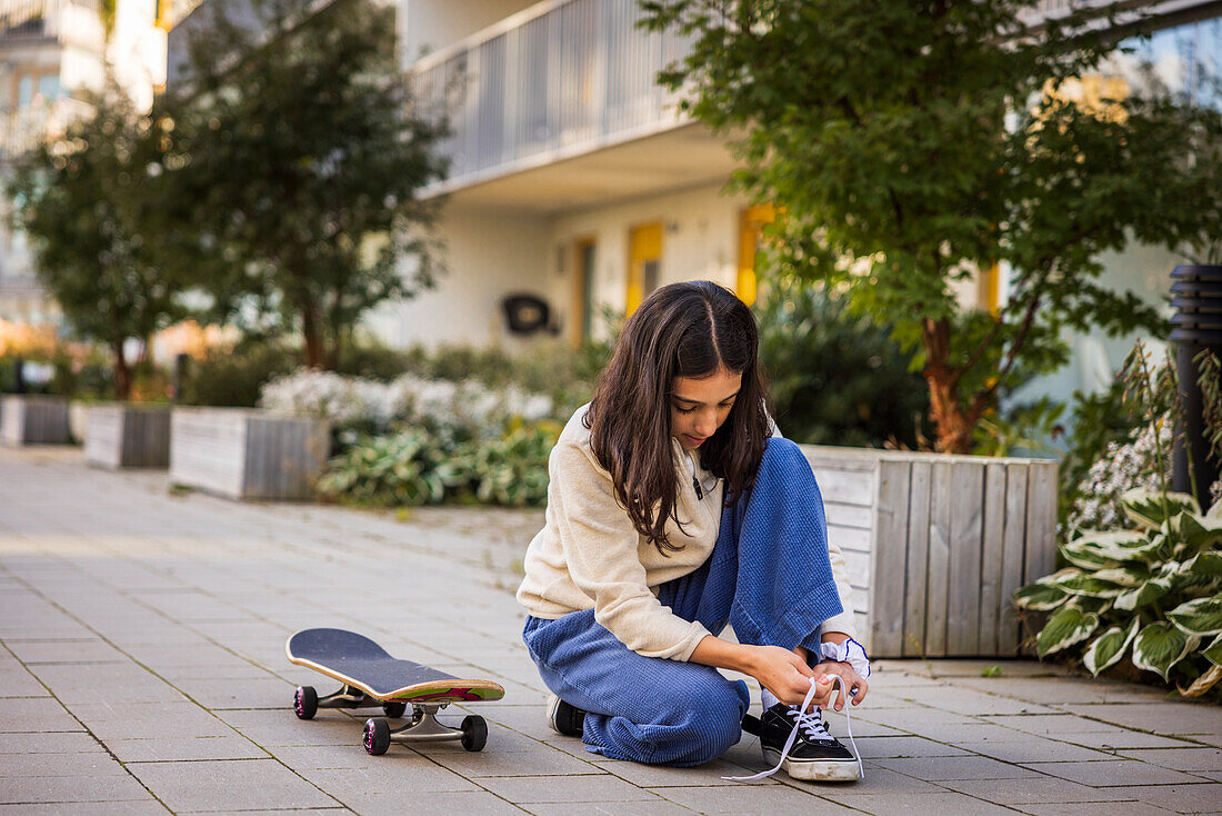 Girl skateboarder tying shoes