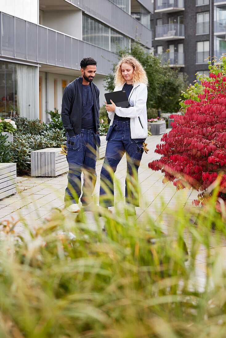 Male and female worker in front of residential building