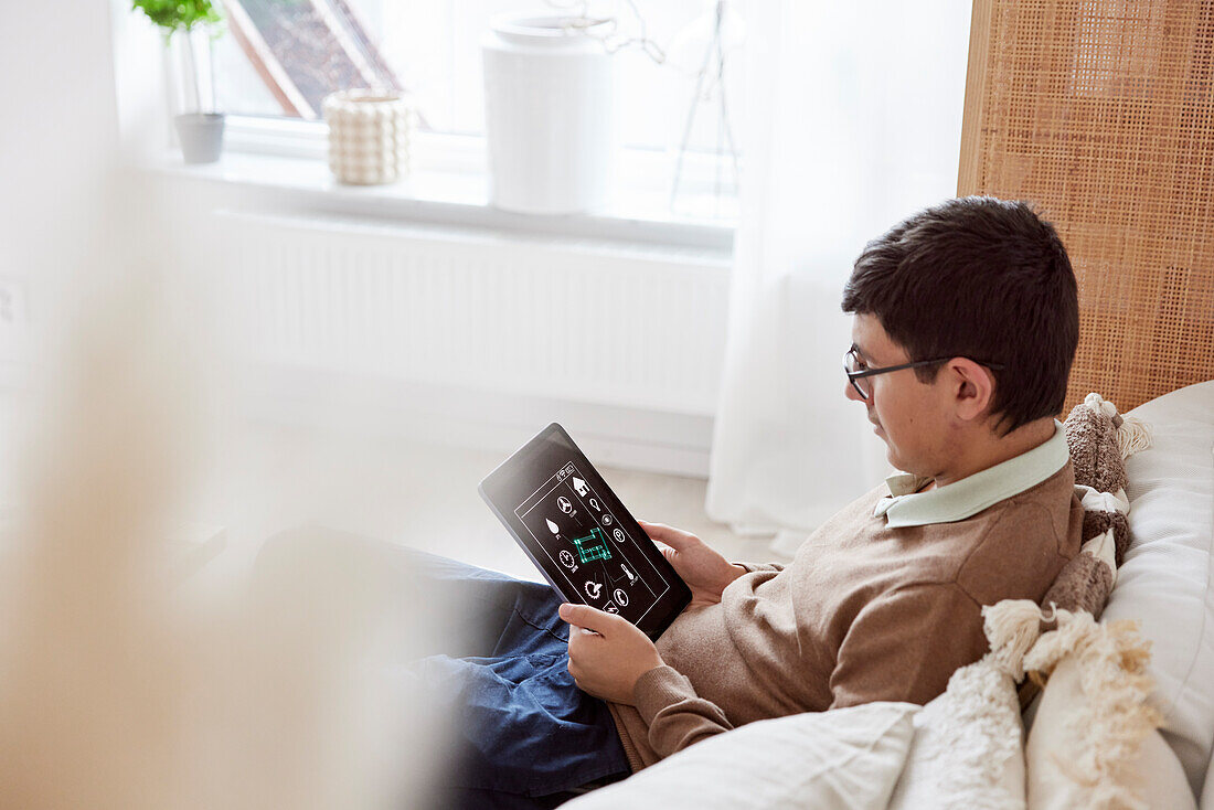 Teenage boy sitting on sofa and using tablet