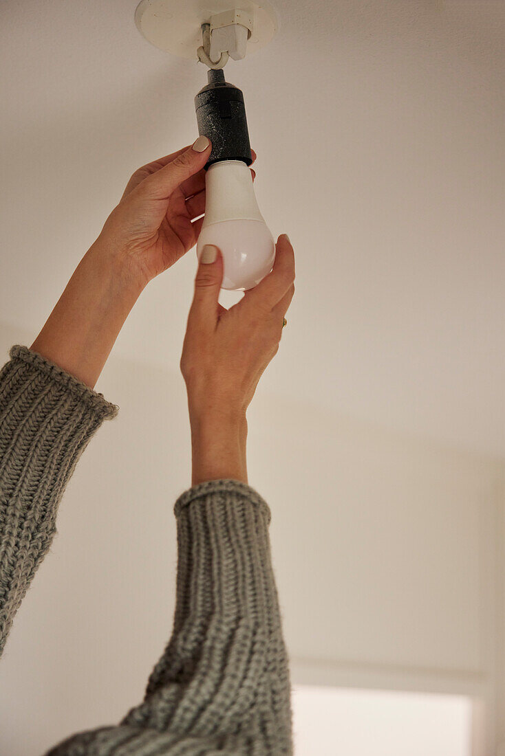 Woman's hands changing light bulb