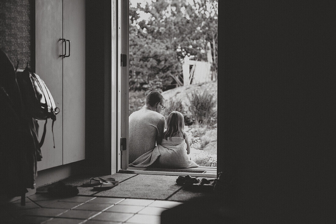 Father and daughter sitting at doorstep