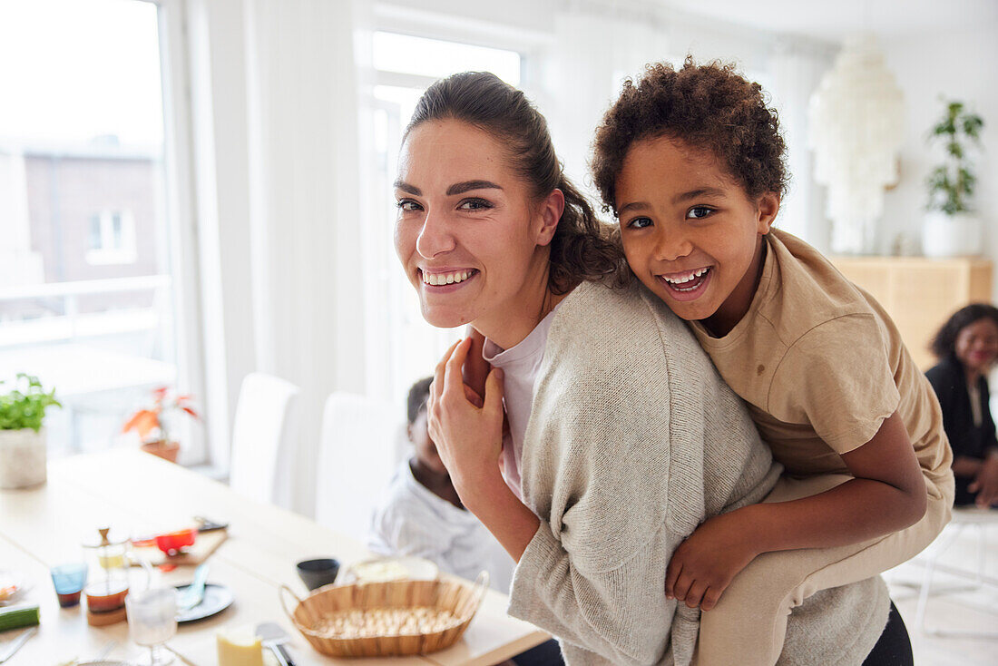 Portrait of mother giving son piggyback ride at home