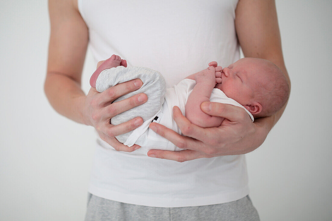 Männerhand hält neugeborenes Baby