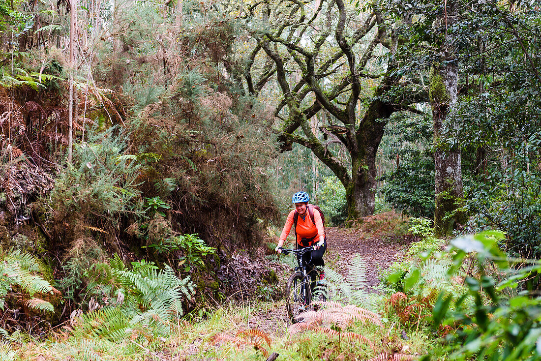 Woman mountain biking through forest
