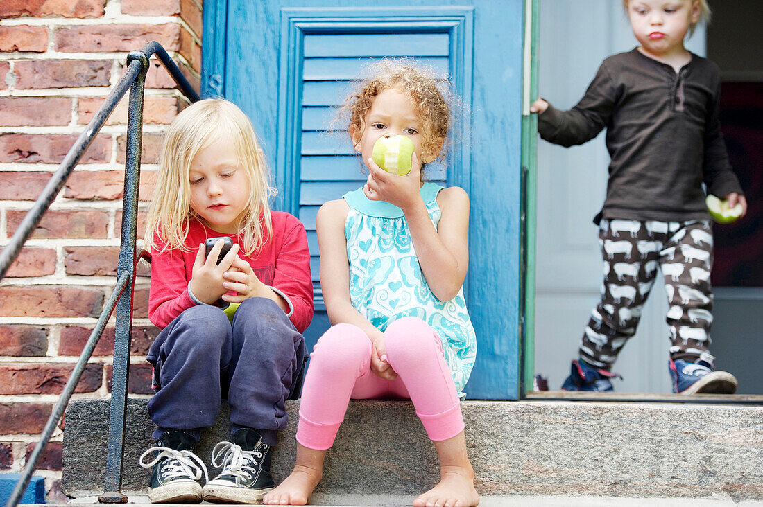 Kinder, die auf einer Treppe sitzen und Äpfel essen