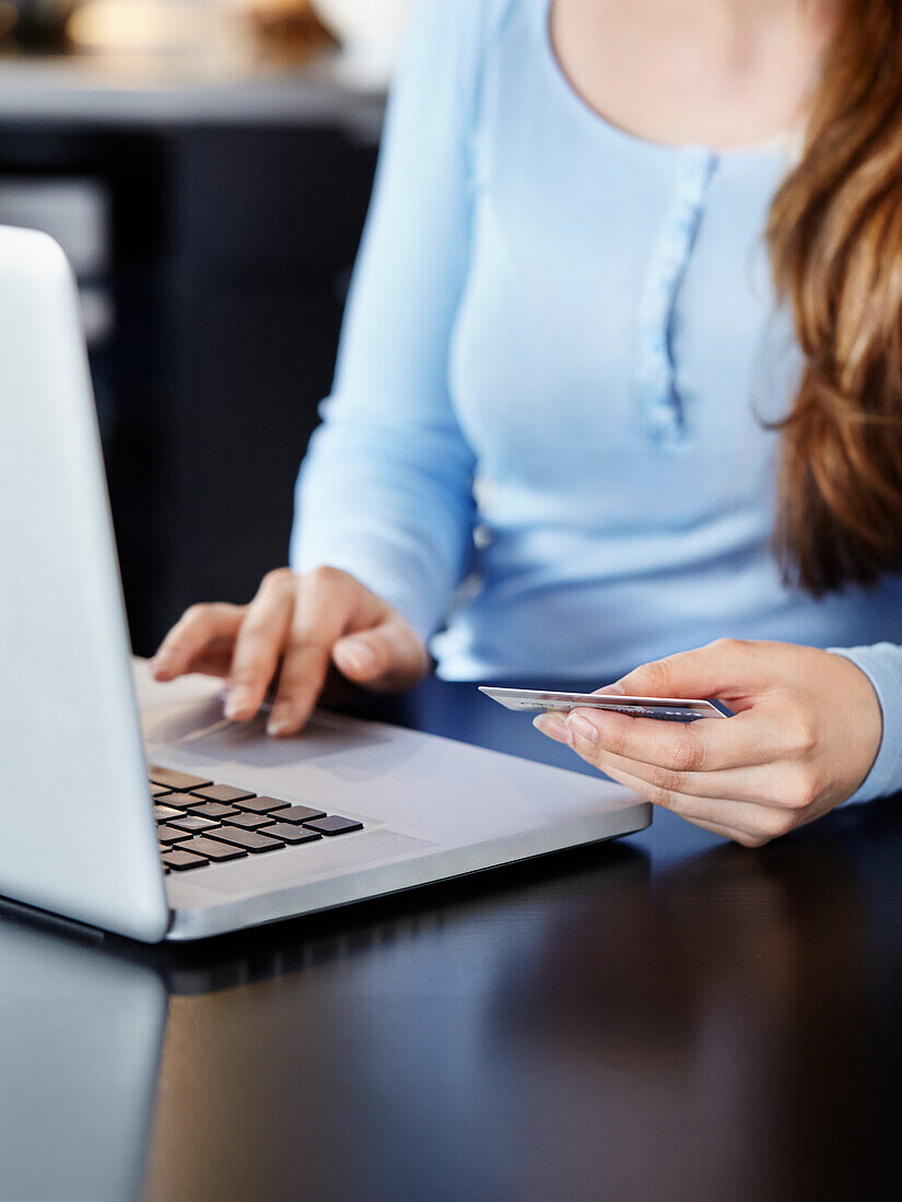 Woman holding credit card and using laptop