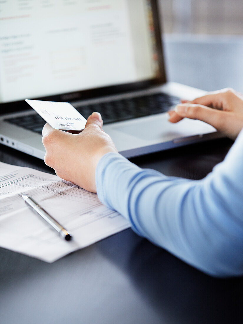 Woman holding credit card and using laptop