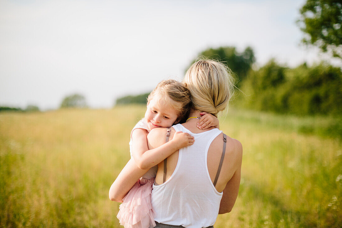 Mother carrying daughter in meadow