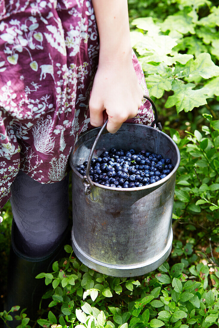 Frau trägt Eimer mit Blaubeeren