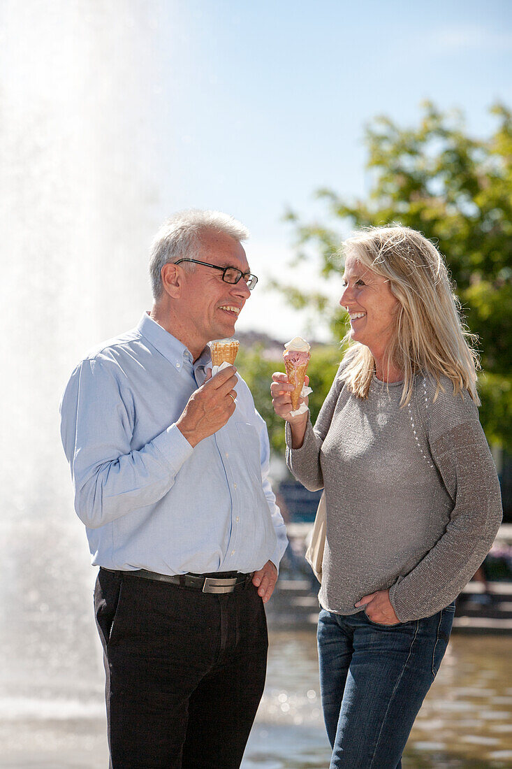 Mature couple eating ice creams in park