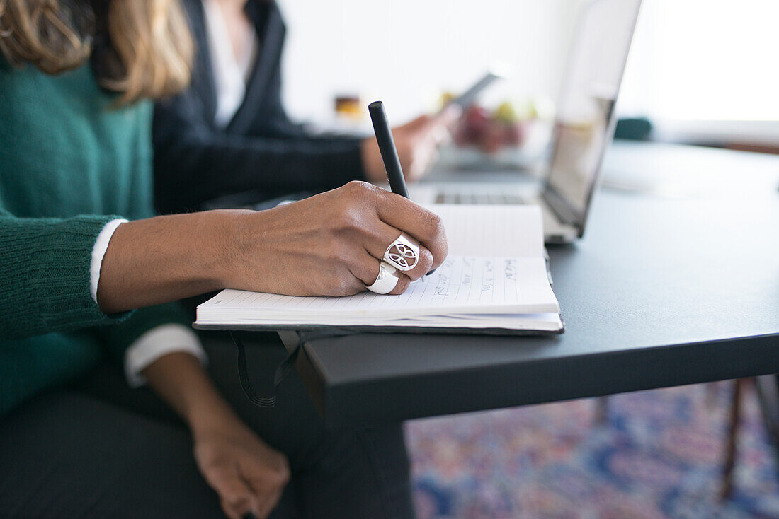 Businesswoman writing in diary in office