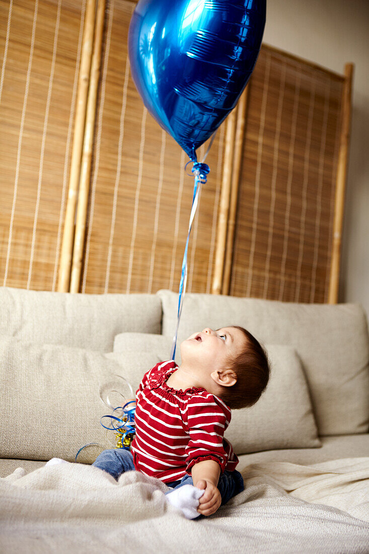 Baby boy looking at blue balloon
