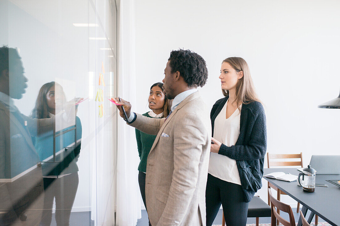 Man and women putting adhesive notes on glass