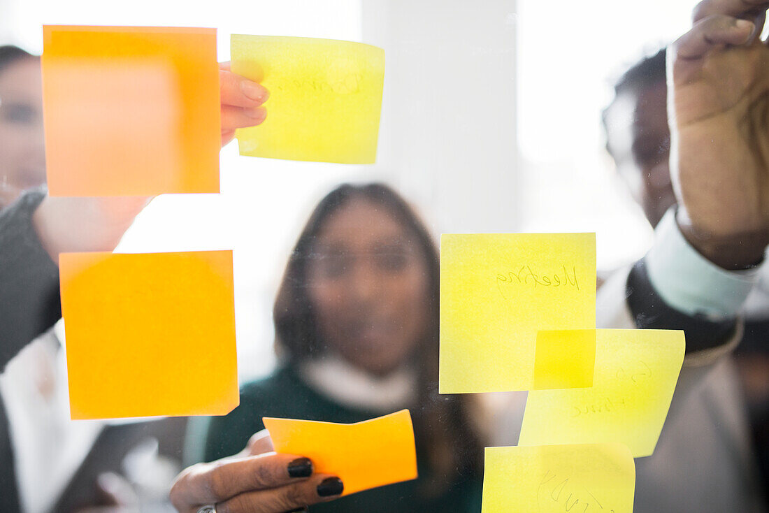 People putting adhesive notes on glass