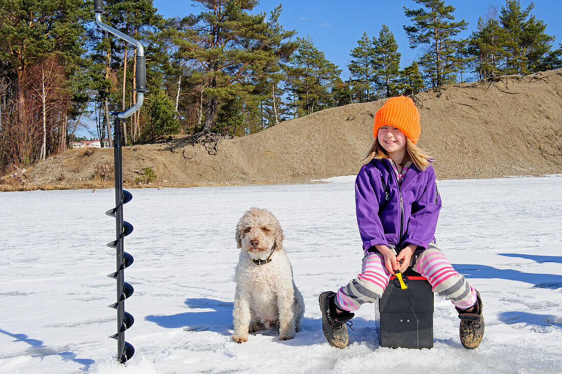 Girl sitting on ice with dog
