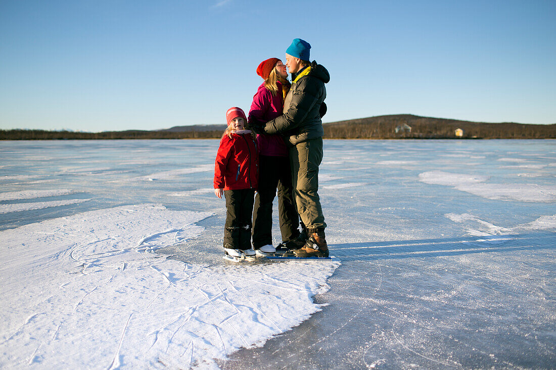 Parents with daughter skating on frozen lake