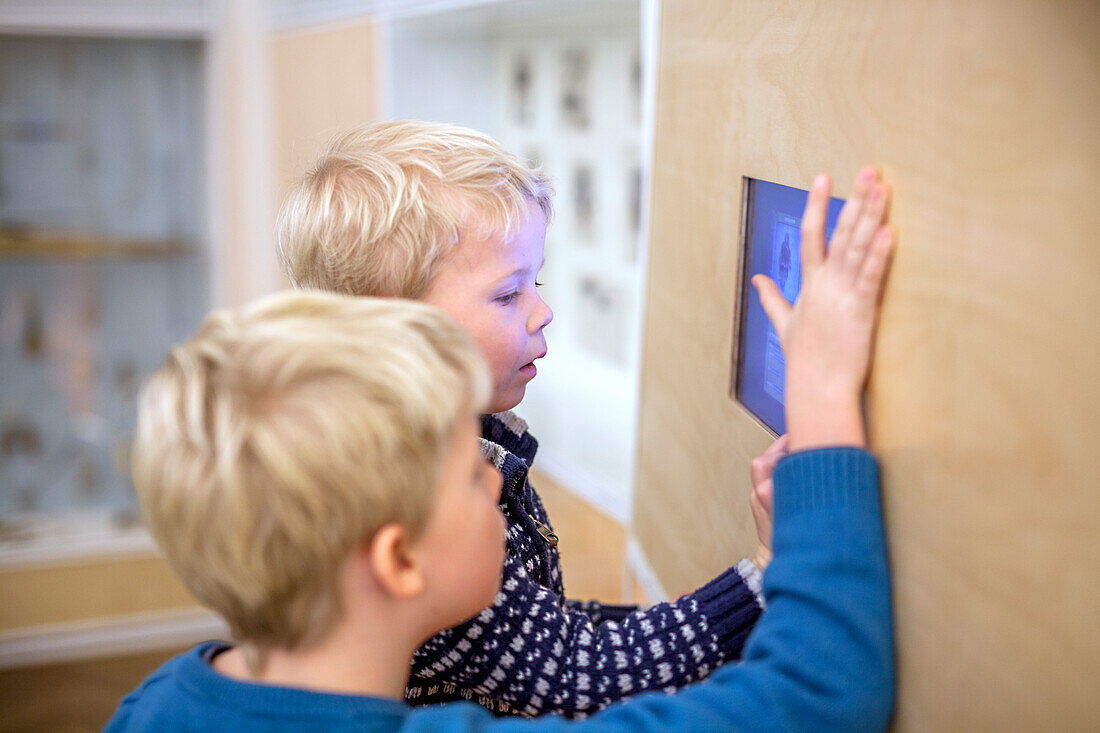 Jungen schauen auf einen Bildschirm im Museum