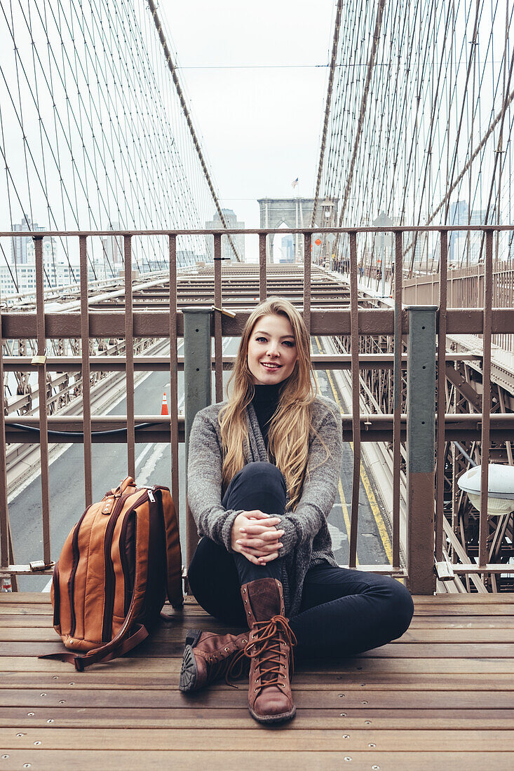 Young woman sitting on bridge