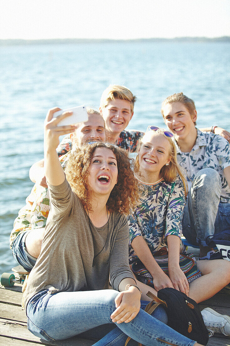 Happy friends taking selfie at water