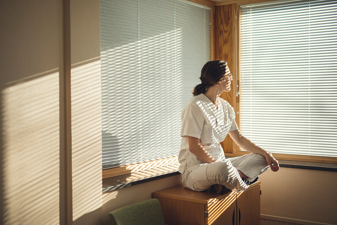 Female doctor sitting by window
